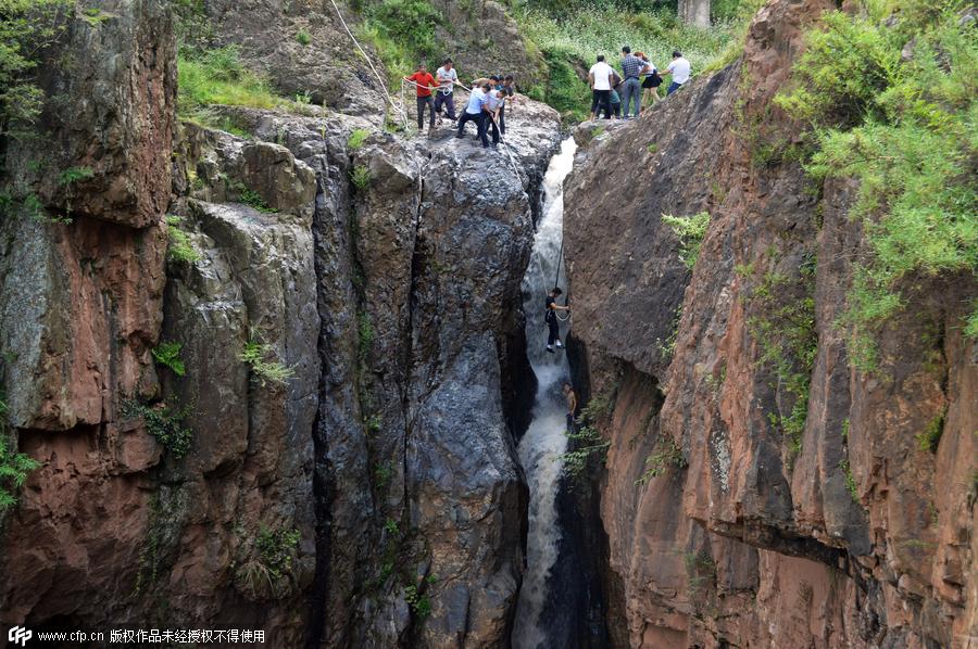 Boy plucked from cliff after falling into waterfall in SW China