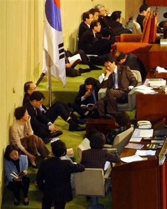 Lawmakers of the main opposition Grand National Party occupy the place of the chairman of the National Assembly in Seoul Friday, Dec. 31, 2004. South Korea (news - web sites) will be left without a national budget and its troops deployed in Iraq (news - web sites) on an unauthorized mission if a weekslong deadlock in parliament isn't resolved before midnight Friday. (AP Photo/ Lee Jin-man) 