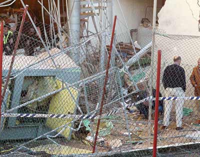 Policemen look through debris at the site where a bomb exploded in a seaside hotel in southeast Spain, January 30, 2005. The bomb exploded after a warning call in the name of the Basque separatist group ETA, and slightly injured one tourist. [Reuters]