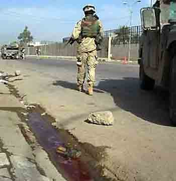 A U.S. soldier walks the scene after two suicide bomb attacks in Baquba, 65 kms (43 miles) north of Baghdad, May 15, 2005. Two suicide bombers attacked the convoy of the governor of Iraq's Diyala province. Raad Rashid was not hurt in the attack. (Stringer/Iraq/Reuters