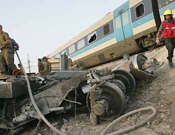 Israeli rescue workers survey wreckage, following a train crash accident near the Kibbutz Revadim on June 21, 2005. [Reuters]