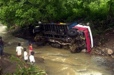 Children look at a bus that was carried away by flood waters which was transporting several players and fans of a nonprofessional soccer team in Cuisnahuat, El Salvador, some 45 miles west of San Salvador, Monday, June 27, 2005.