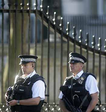 Armed police officers patrol in Whitehall near the Houses of Parliament in central London, August 4, 2005. Exactly four weeks after suicide bombers struck the British capital, thousands of police took to the streets on Thursday in a high visibility security operation to reassure jittery Londoners. 