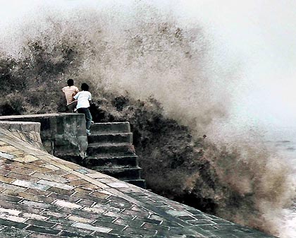 Chinese tourists watch the tide on the bank of Qiantang River in Hangzhou September 7, 2005. Tides waves are seen each year during the eighth month of the lunar calendar, with the most violent tide reaching a height of nine metres.