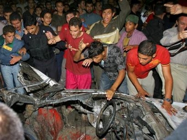 Palestinians gather around the wreckage of a car after it was hit by an Israeli missile strike in the Jebaliya refugee cam, adjacent to Gaza City, in the northern Gaza Strip, Thursday Oct. 27, 2005.