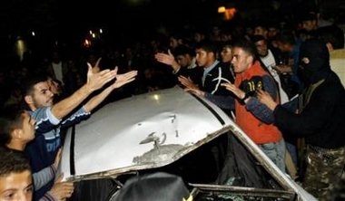 Palestinians gather around the wreckage of a car after it was hit in an Israeli missile strike in Gaza City, Wednesday Dec. 14, 2005.