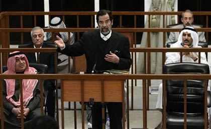 Former Iraqi leader Saddam Hussein gestures as he addresses the court as Sultan Hashim Ahmad al-Tai, first row left, Sabir al-Douri, second row left, Farhan Mutlaq Saleh, second row, right, Ali Hassan al-Majid third row left, and Taher Tawfiq al-Ani, third row right, listen during their trial held in Baghdad's heavily fortified Green Zone, Wednesday Oct. 11, 2006. Saddam Hussein took his seat in the dock in his genocide trial Wednesday, a day after the presiding judge threw him out of court in a raucous session during which witnesses testified that women were raped while in detention during a 1980s crackdown on the Kurds. With Saddam and his six co-defendants sitting quietly, chief judge Mohammed Oreibi al-Khalifa called on a Kurdish witness to take the stand. (AP Photo